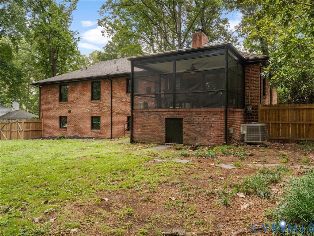 Brick exterior featuring a screened porch with a ceiling fan, a chimney, and a wood privacy fence