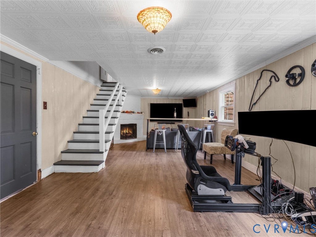 Wood-finish flooring throughout, featuring a white staircase with dark treads, a corner fireplace, and a textured ceiling