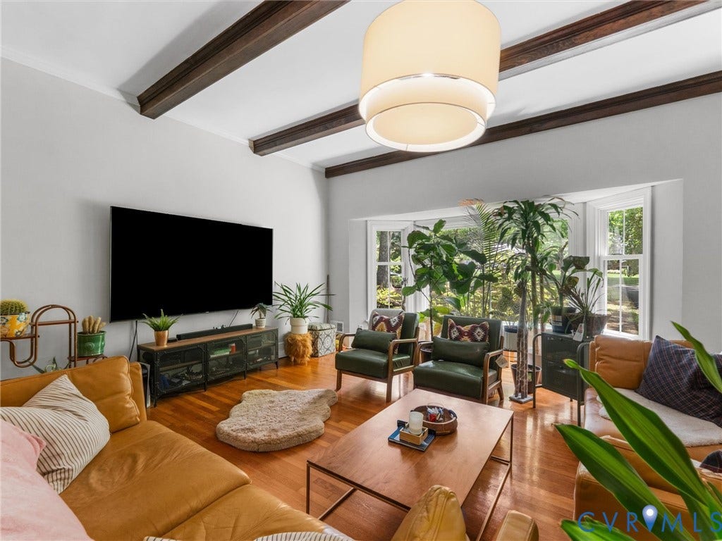 Sophisticated living room featuring exposed wooden ceiling beams, recessed ceiling lighting, and hardwood flooring throughout