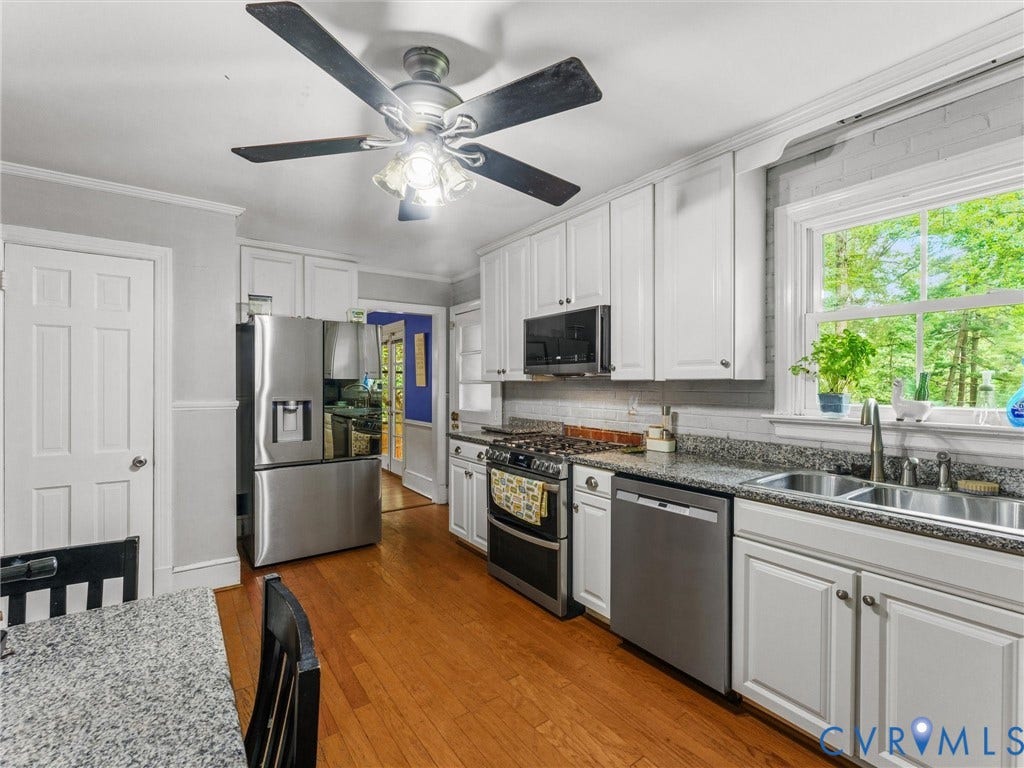 White cabinetry, stainless steel appliances, wood-finish flooring, and granite-style countertops