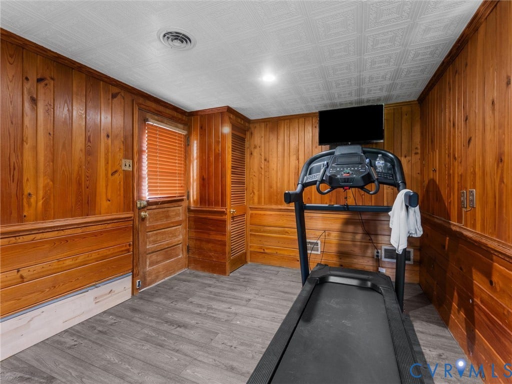 Wood paneling, wood-finish flooring, recessed lighting, and a paneled door
