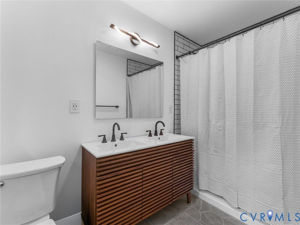 Double vanity with white undermount sinks, wood-finish cabinetry, and matte black fixtures