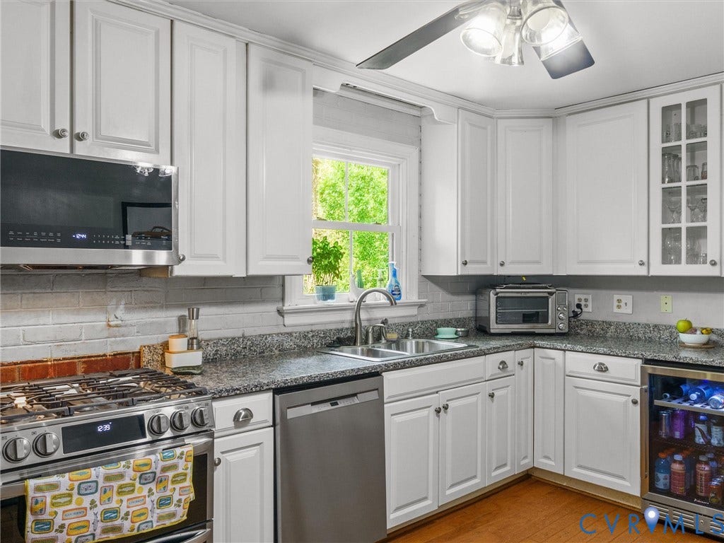 White cabinetry, stainless steel appliances, granite countertops, and a tile backsplash
