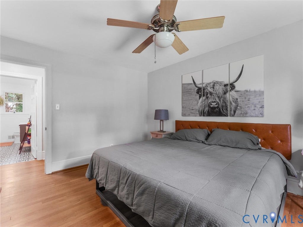 Hardwood flooring, ceiling fan with wood-finish blades, and light gray wall paint