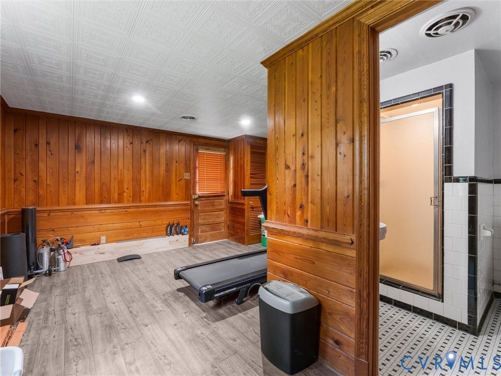 Wood-finish flooring, wood paneling, recessed lighting, and a white tile ceiling with integrated lighting