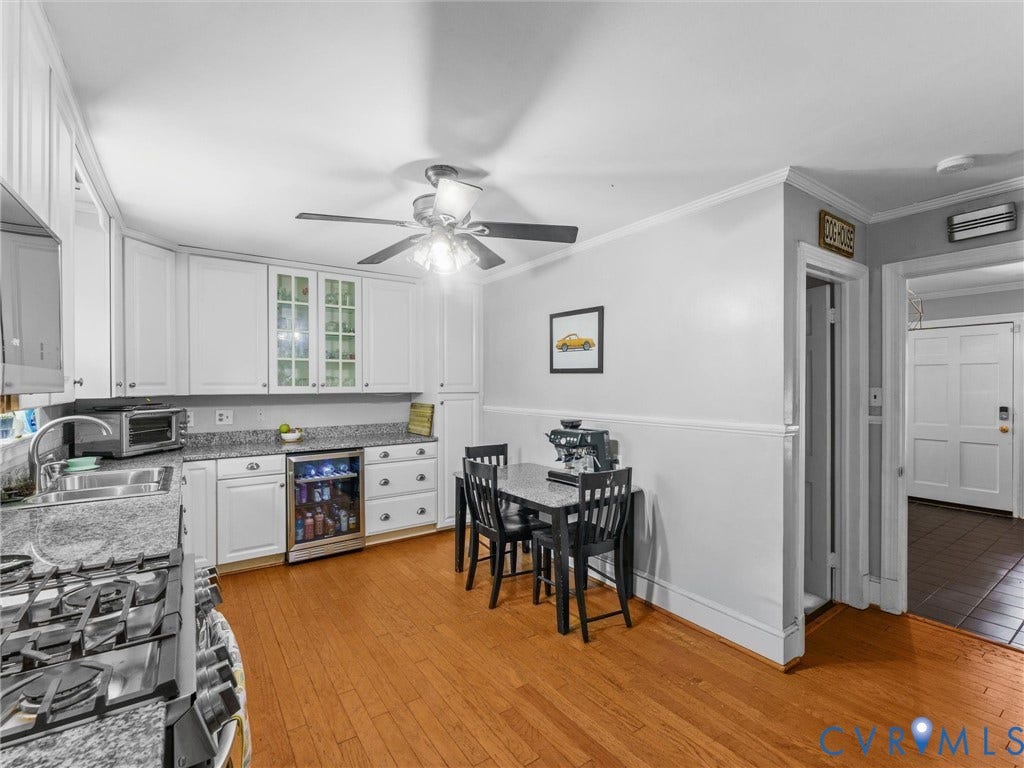 White cabinetry with glass-front accents, light-toned countertops, and wood-finish flooring