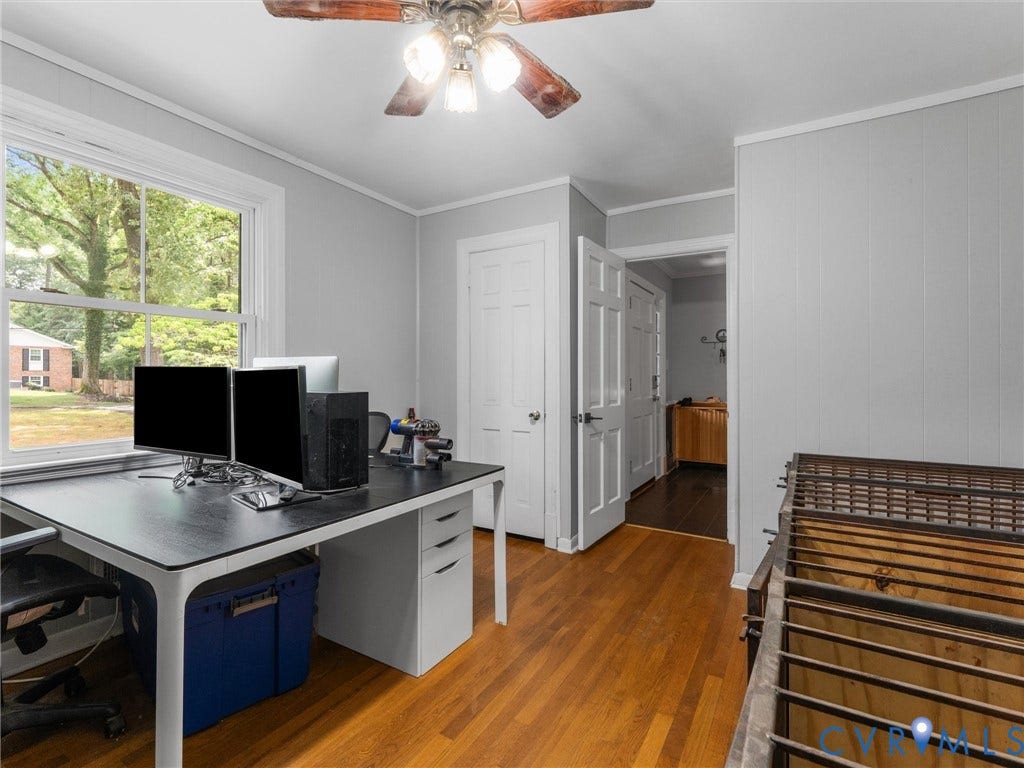 Wood-finish flooring, white trim, ceiling fan, and white paneled doors