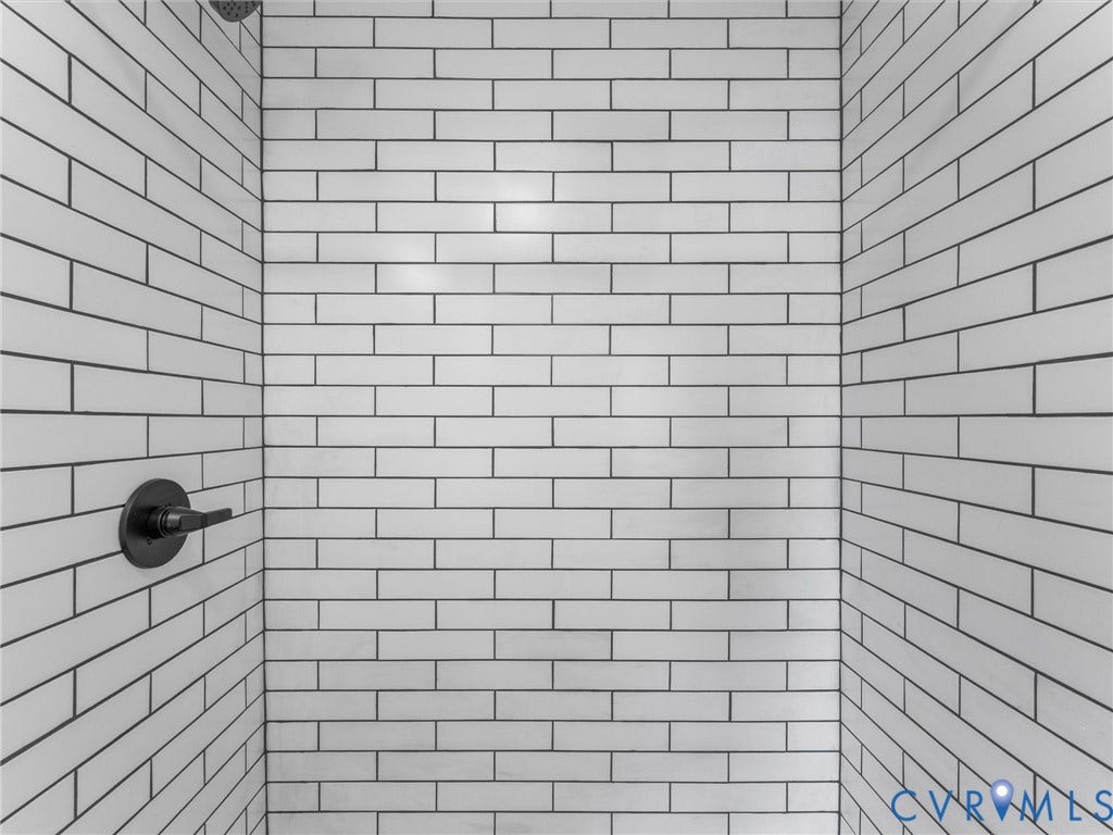 White subway tile shower enclosure with dark grout, matte black shower head, and matte black shower controls