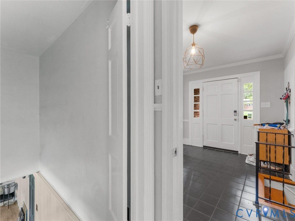 Entryway featuring dark tile flooring, a paneled front door with sidelights, and a geometric pendant light fixture