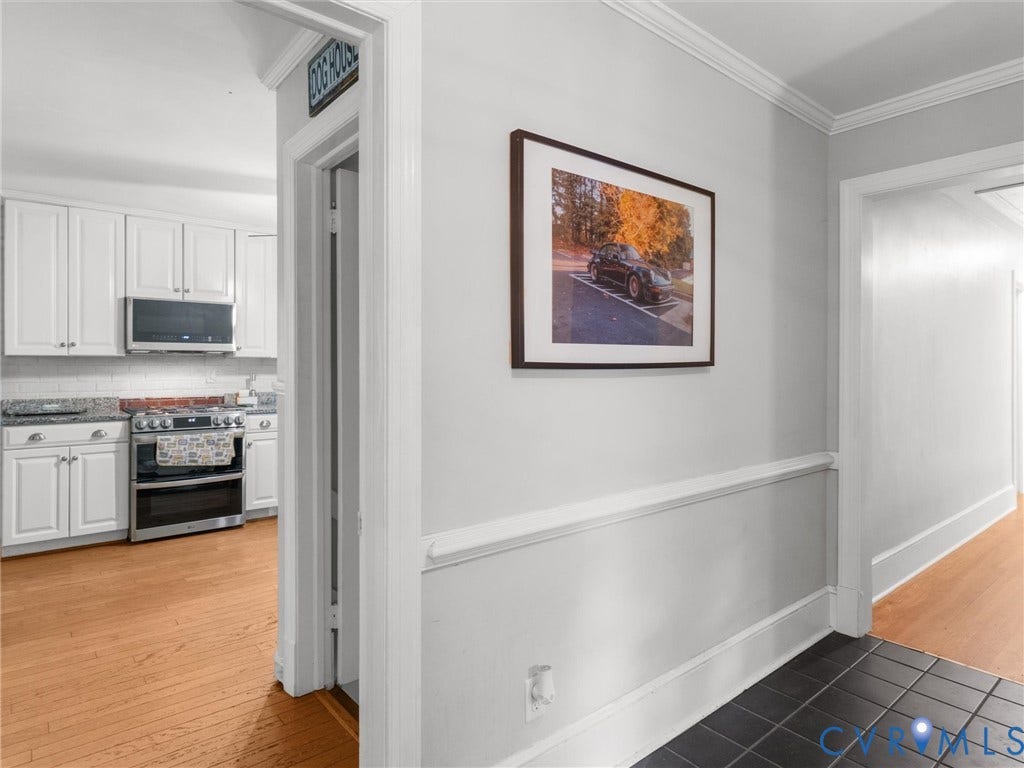 Kitchen featuring wood-finish flooring, white cabinetry, and stainless steel appliances
