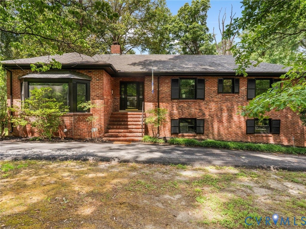 Brick exterior with a prominent bay window, black framed windows, and matching black shutters