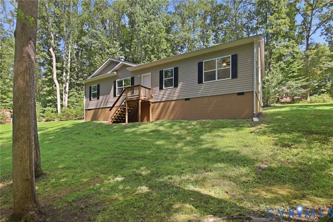 2575 Log Cabin Road, Maidens, VA 23102 Wooded setting with a light-colored siding exterior, dark shutters, and an elevated wood deck entry with stairs