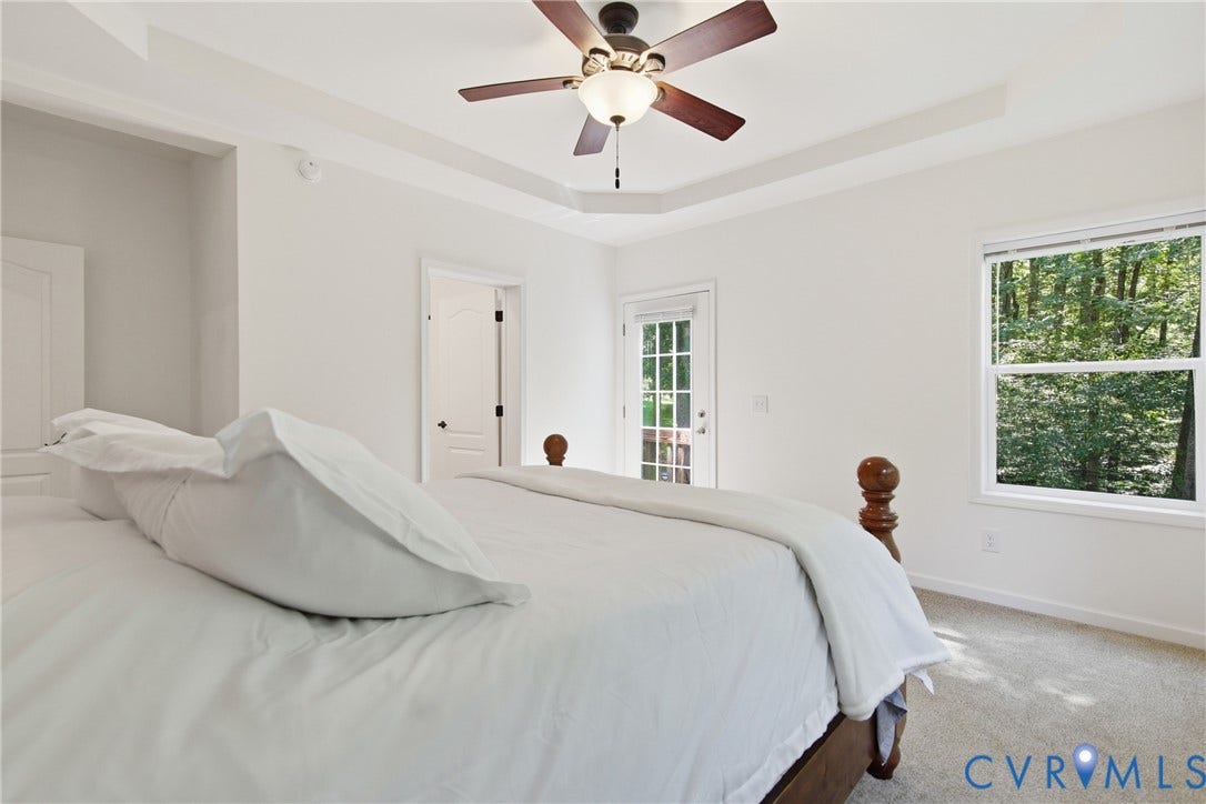 2575 Log Cabin Road, Maidens, VA 23102 Tray ceiling with a ceiling fan, light gray carpeting, white walls, and a glass-paned exterior door