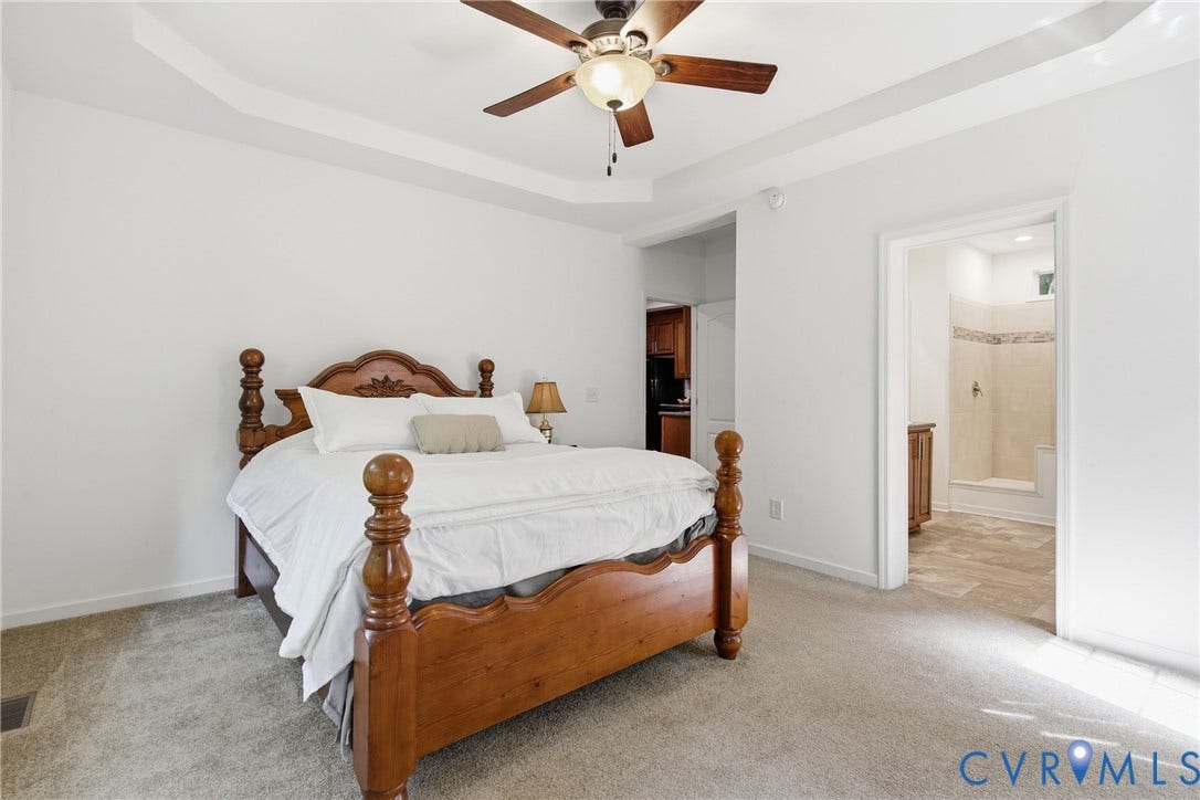 2575 Log Cabin Road, Maidens, VA 23102 Tray ceiling with a ceiling fan, carpet flooring, and an open doorway to En Suite Bathroom with a spa like modern shower and walk in closet.