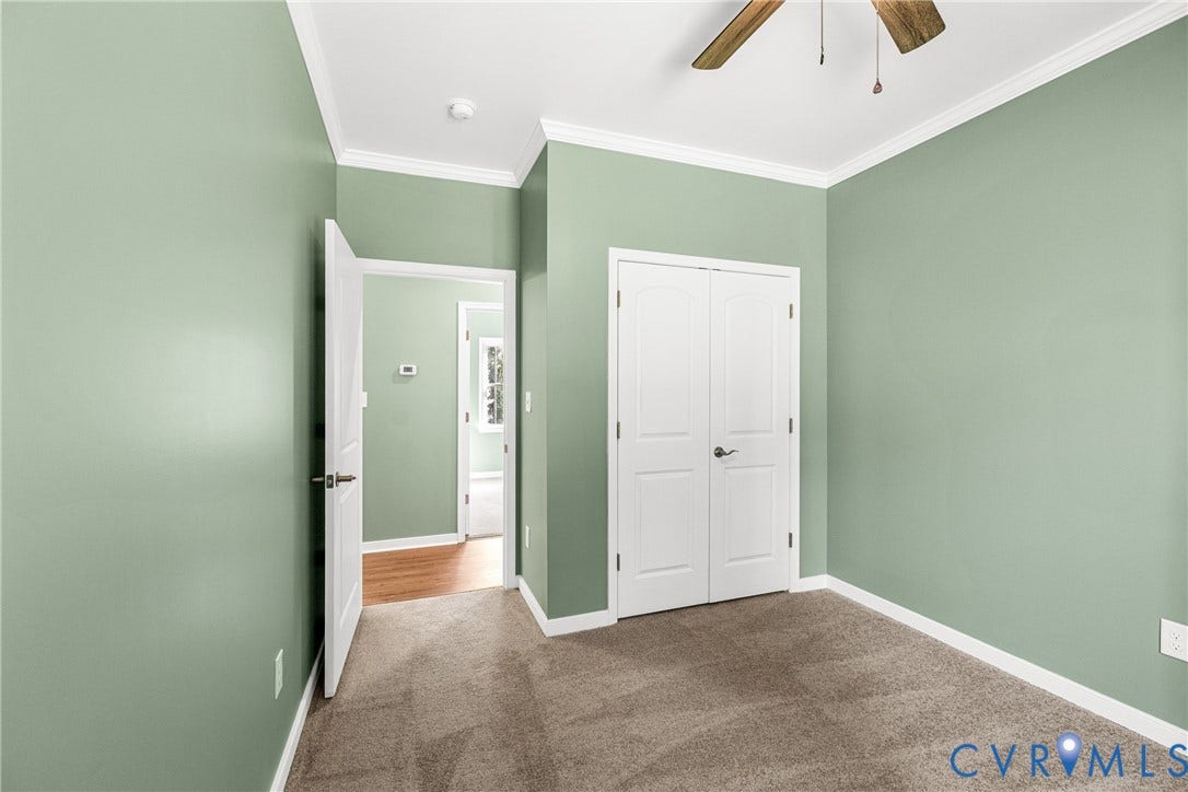 Carpeted flooring, double closet doors, ceiling fan, crown molding.