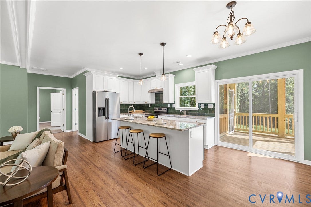 Open-concept kitchen with white cabinetry, stainless steel appliances, and a central island with countertop seating