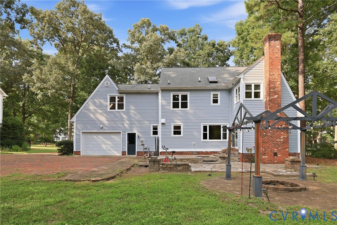 505 Martineau Drive, Chesterfield, VA 23836 Exterior featuring light blue siding, a brick chimney, a two-car garage, and a paver patio with an attached pergola