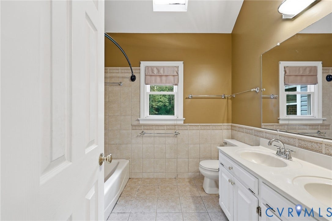 505 Martineau Drive, Chesterfield, VA 23836 Bathroom featuring a double vanity with integrated sinks, a tiled tub surround, and a skylight