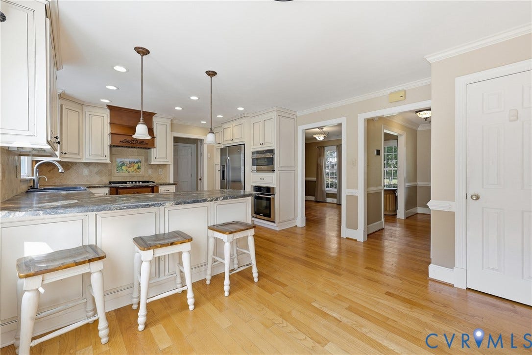 505 Martineau Drive, Chesterfield, VA 23836 Kitchen featuring white cabinetry, a central island with countertop seating, stainless steel appliances, pendant lighting, and wood-finish flooring
