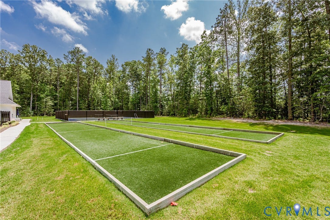 7683 Autumn Leaves Lane, Estates The Groves At New Kent, New Kent, VA 23124 Manicured lawn with two artificial turf bocce courts, bordered by a wooden privacy fence and mature trees