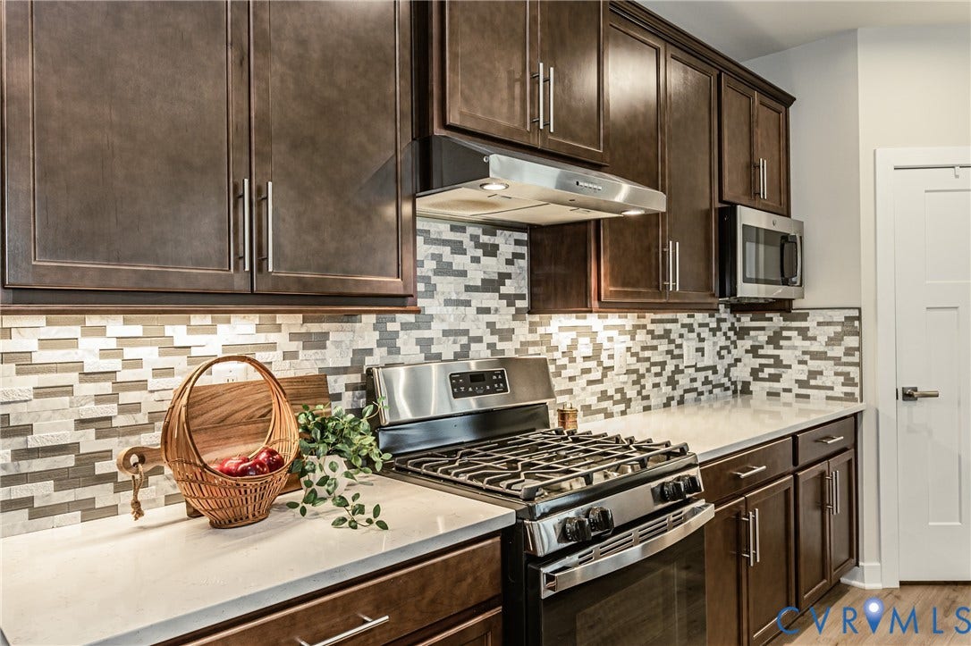 7683 Autumn Leaves Lane, Estates The Groves At New Kent, New Kent, VA 23124 Sleek stainless steel gas range, microwave, and range hood complement dark wood-finish cabinetry