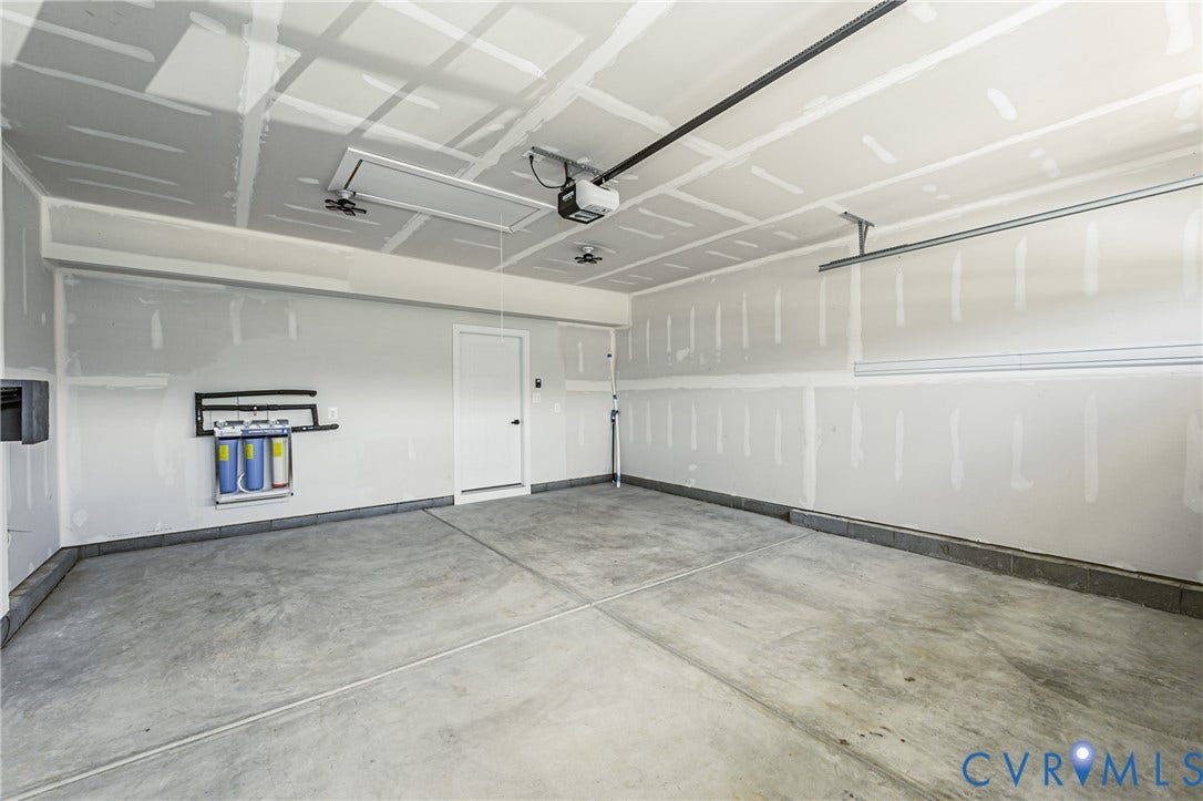 7683 Autumn Leaves Lane, Estates The Groves At New Kent, New Kent, VA 23124 Spacious garage with exposed drywall, concrete flooring, and an installed water filtration system