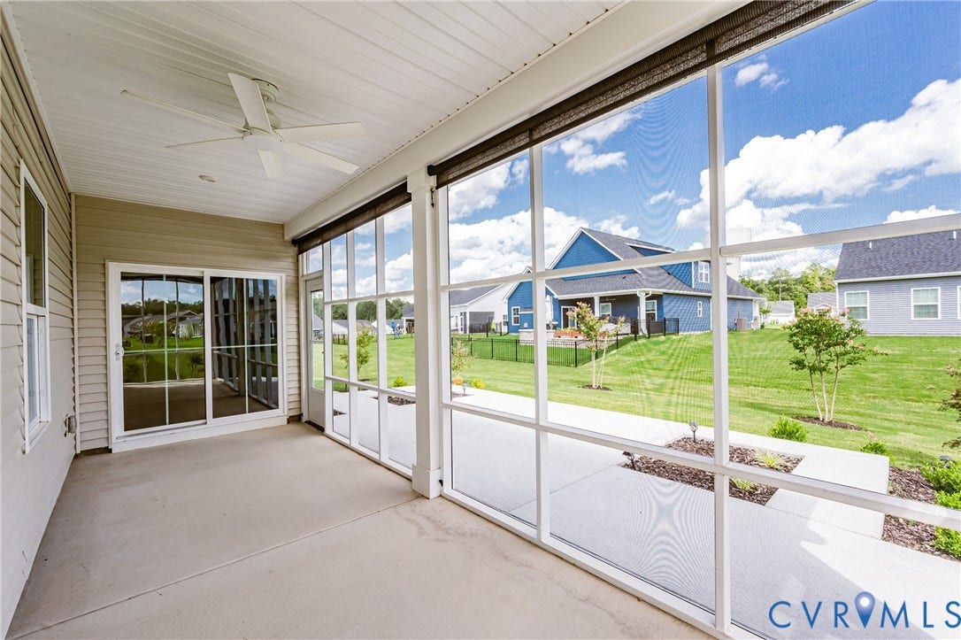 7683 Autumn Leaves Lane, Estates The Groves At New Kent, New Kent, VA 23124 Screened porch with concrete flooring and a ceiling fan, featuring a sliding glass door and a paved walkway