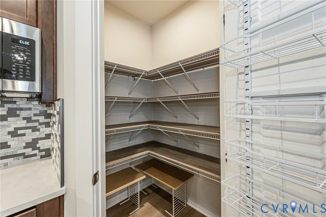 7683 Autumn Leaves Lane, Estates The Groves At New Kent, New Kent, VA 23124 Walk-in pantry featuring wire shelving, wood-finish shelving, and a door-mounted rack system