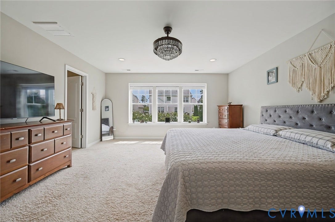 Neutral wall tones, plush carpeting, multi-pane windows, recessed lighting, and a chandelier fixture