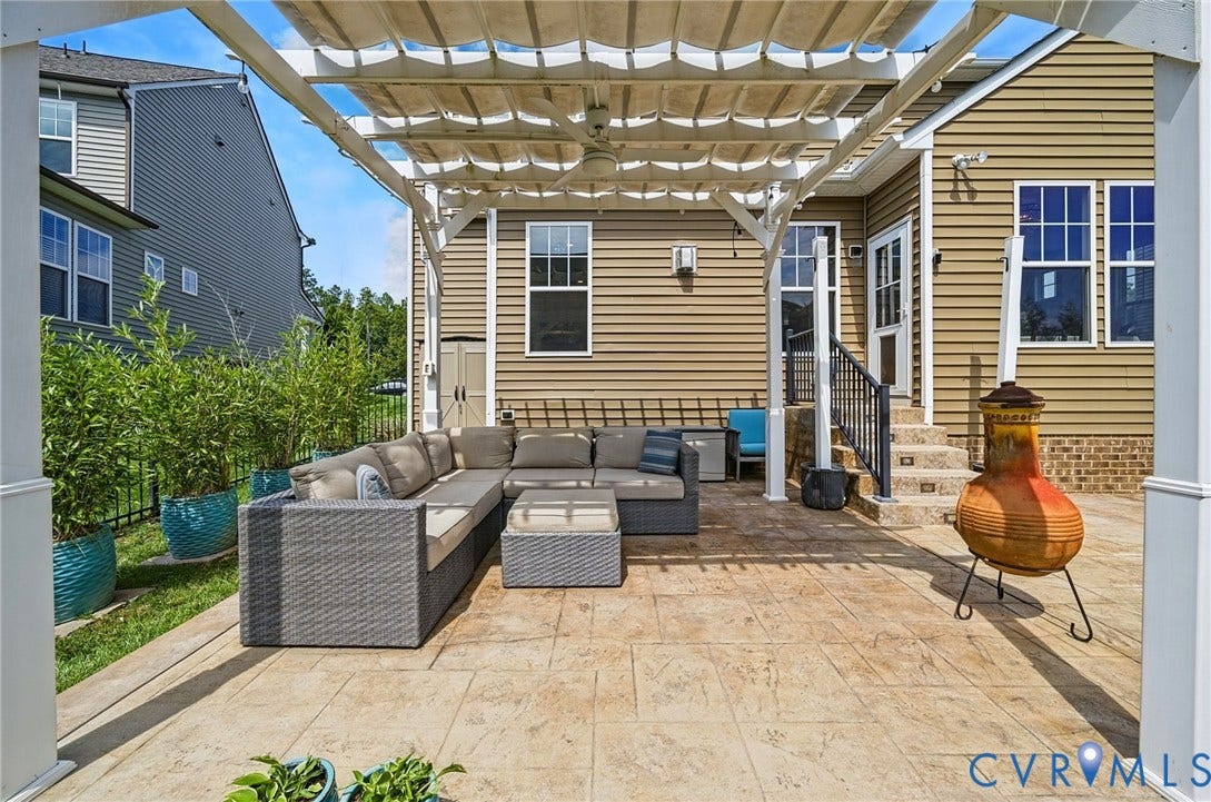 Stamped concrete patio with a white pergola featuring a retractable shade cover