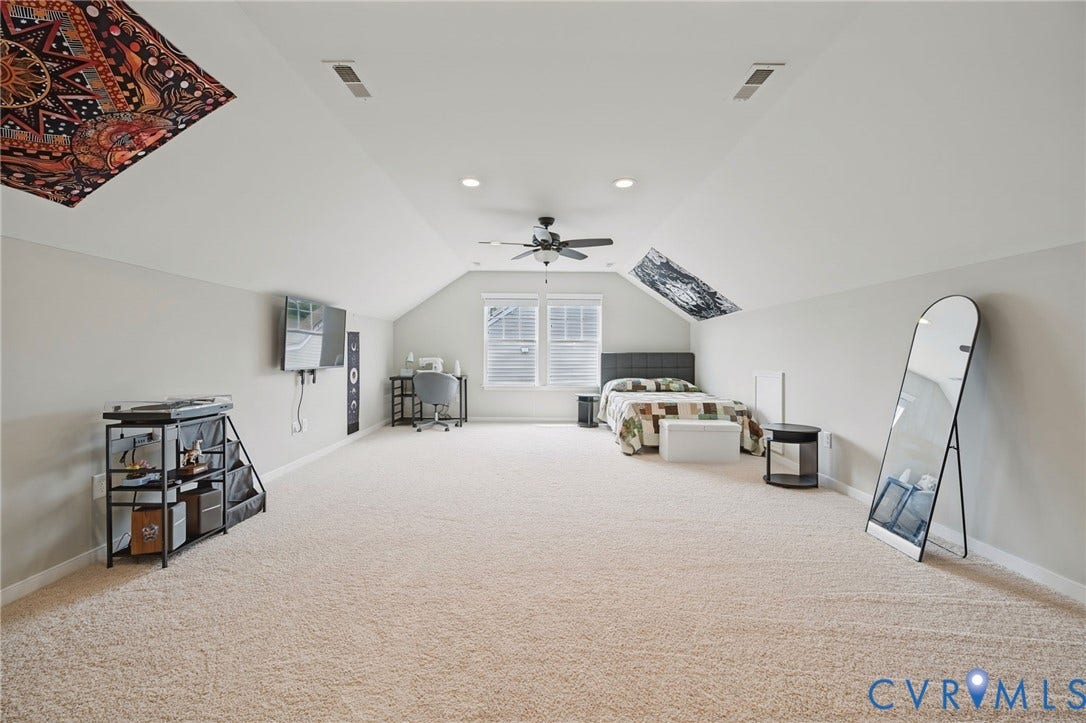 Expansive carpeted room featuring a sloped ceiling, recessed lighting, and a ceiling fan
