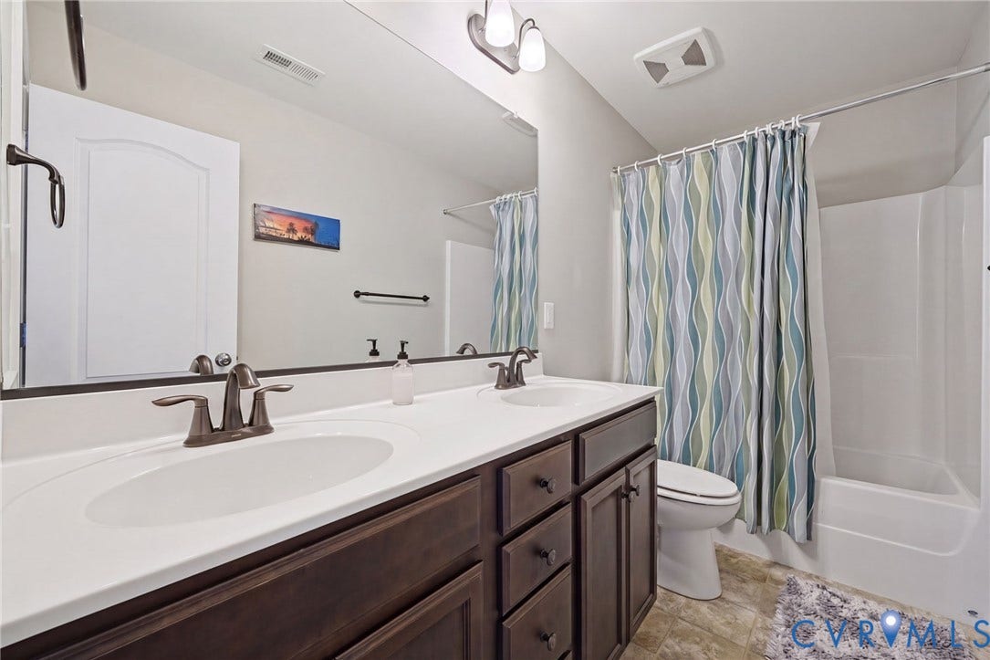 Dual sinks set in a dark wood-finish vanity with a white countertop