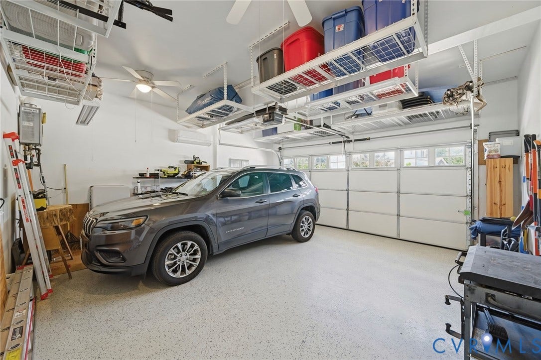 Attached two-car garage featuring overhead storage racks, an epoxy-coated floor, a built-in ceiling fan, and a garage door with window inserts