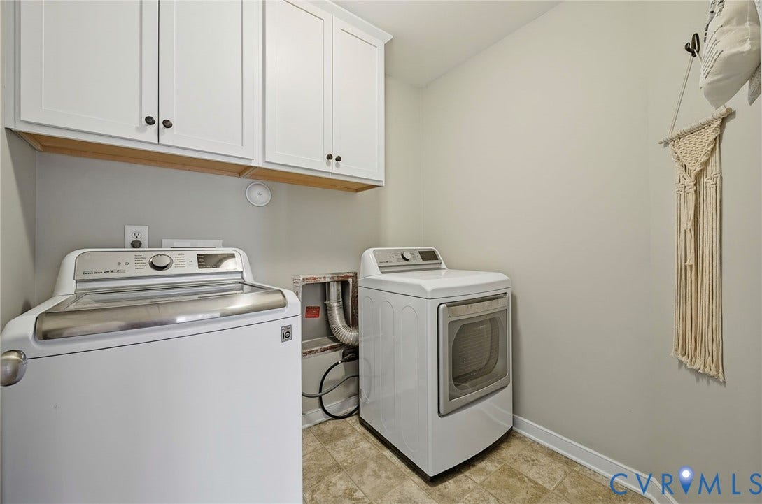 White shaker-style cabinetry with dark hardware, a wood-finish shelf, and light-toned flooring