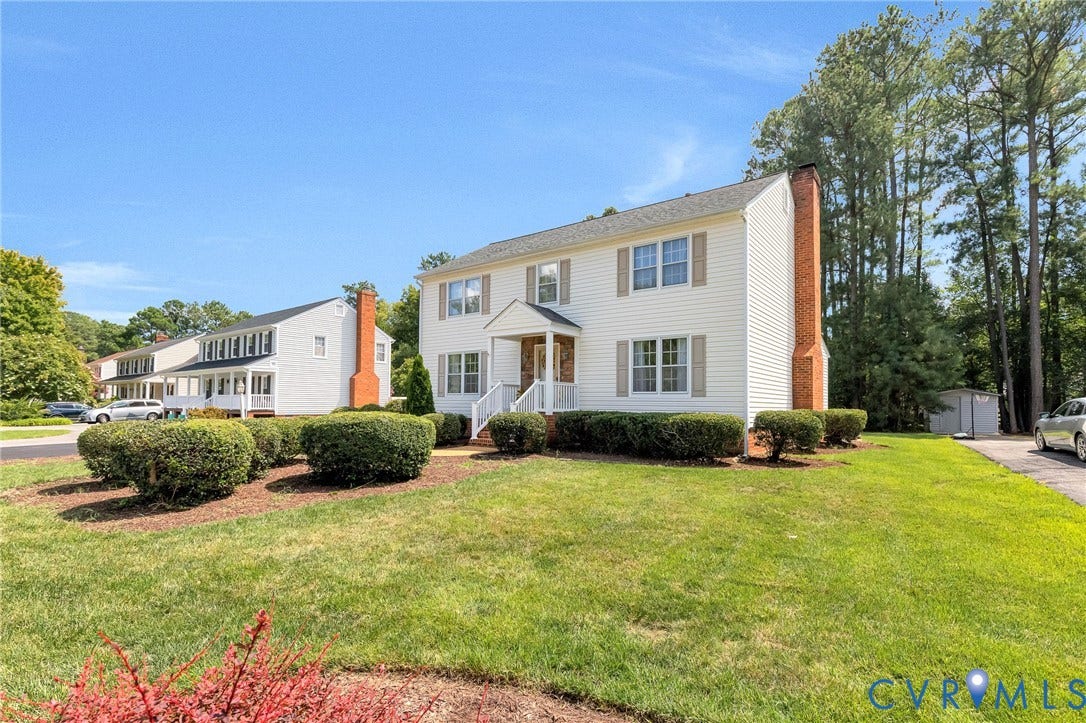 Two-story residence featuring white siding, a covered entry with white railings, and a paved driveway