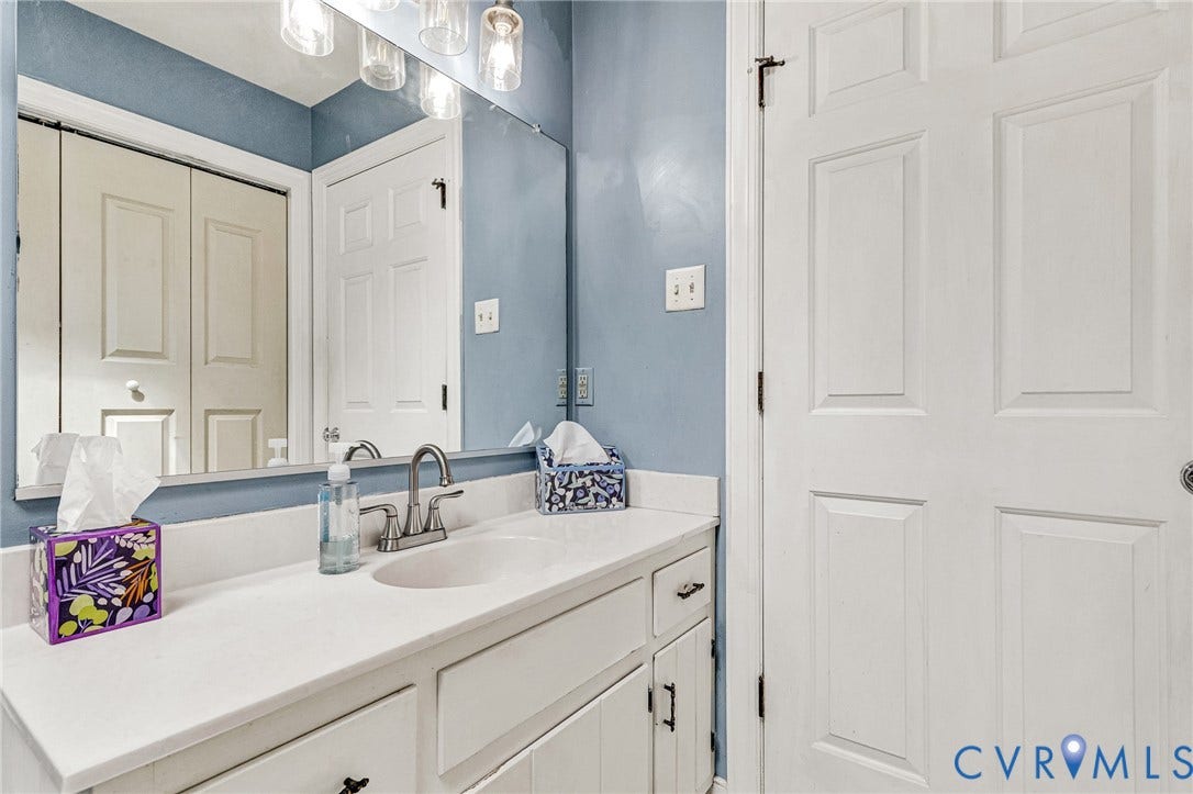 Vanity with a single basin sink, brushed nickel faucet, and a large wall-mounted mirror