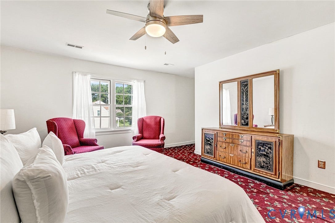 Ceiling fan with integrated lighting, window with white trim, red patterned carpeting, and white walls