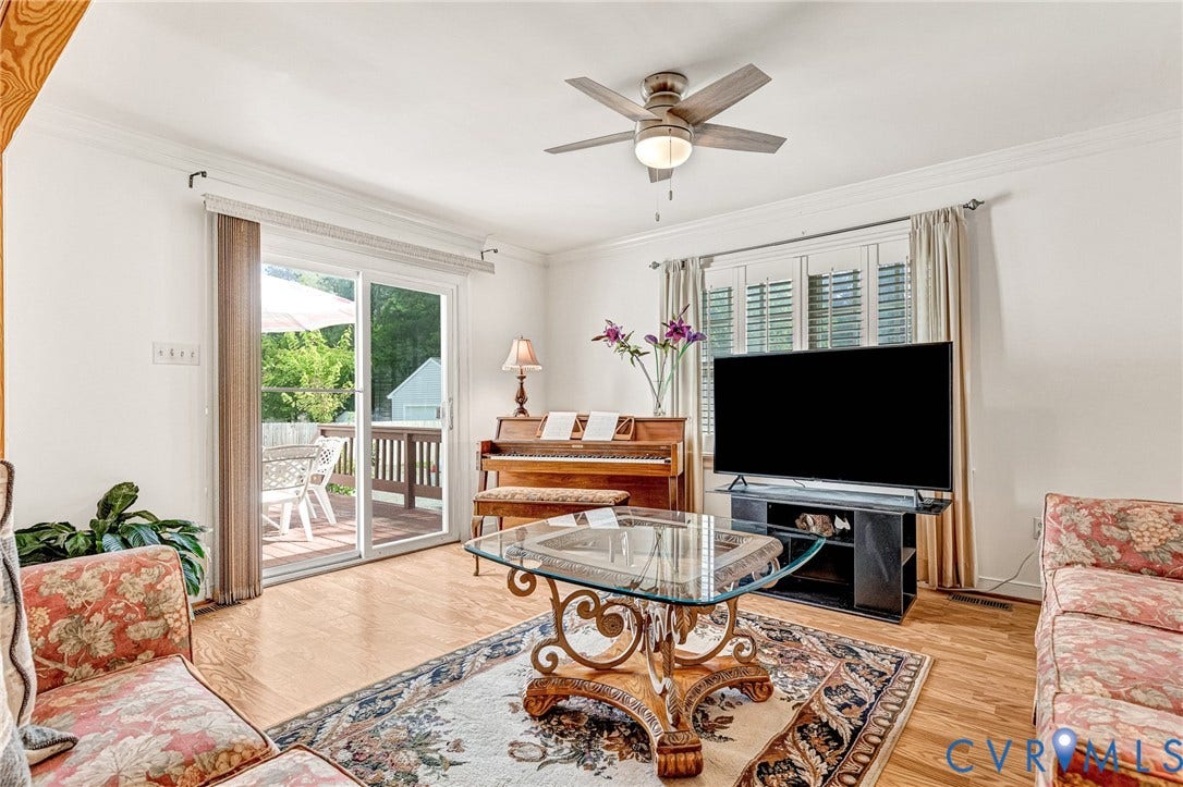 Hardwood-finish flooring, sliding glass door, ceiling fan with integrated lighting, window with white louvered shutters, and crown molding