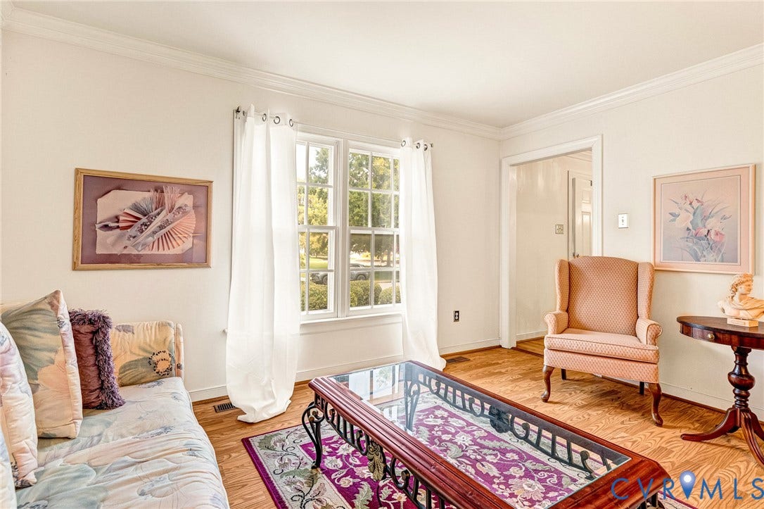 Wood-finish flooring, crown molding, chair rail with wallpaper border, and a brass-tone chandelier