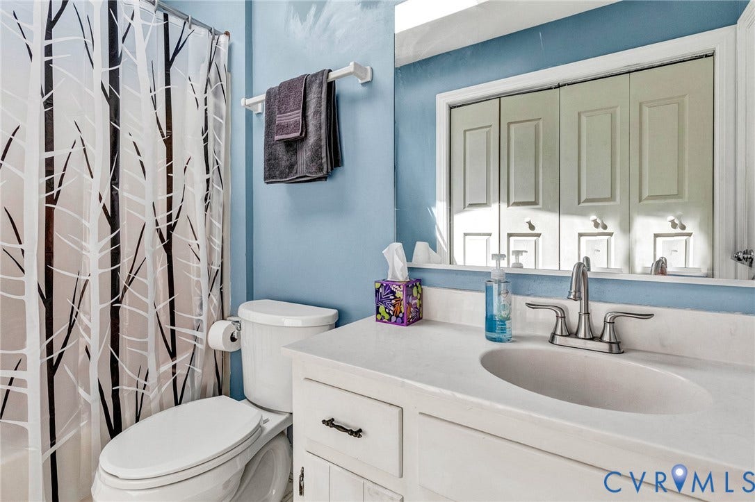 White vanity with a single basin sink, brushed nickel faucet, and a large wall mirror