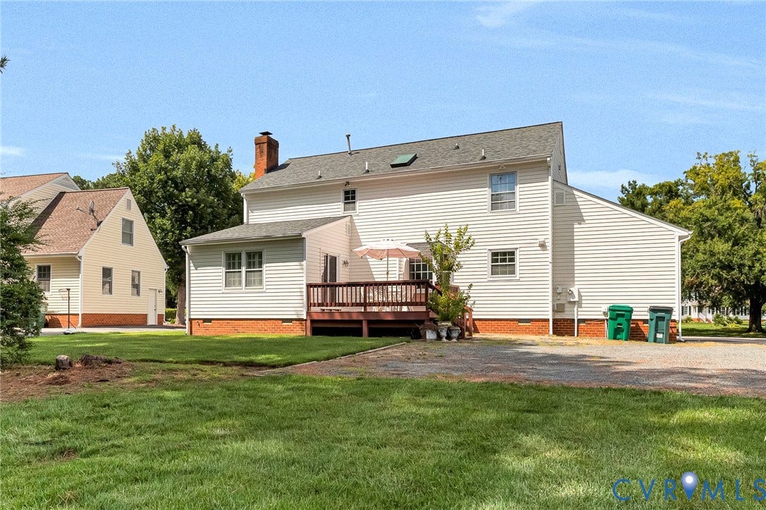 Rear exterior featuring siding, an attached wood deck, and a brick foundation