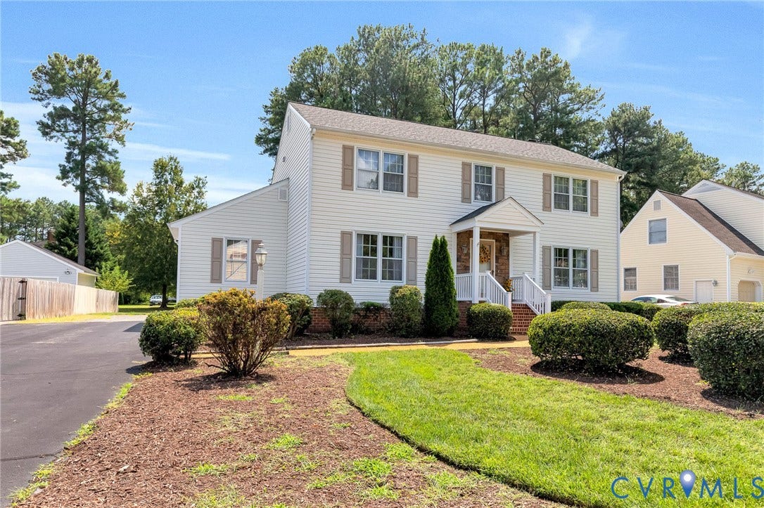 Two-story residence with white siding, brick chimney, and a covered front entry