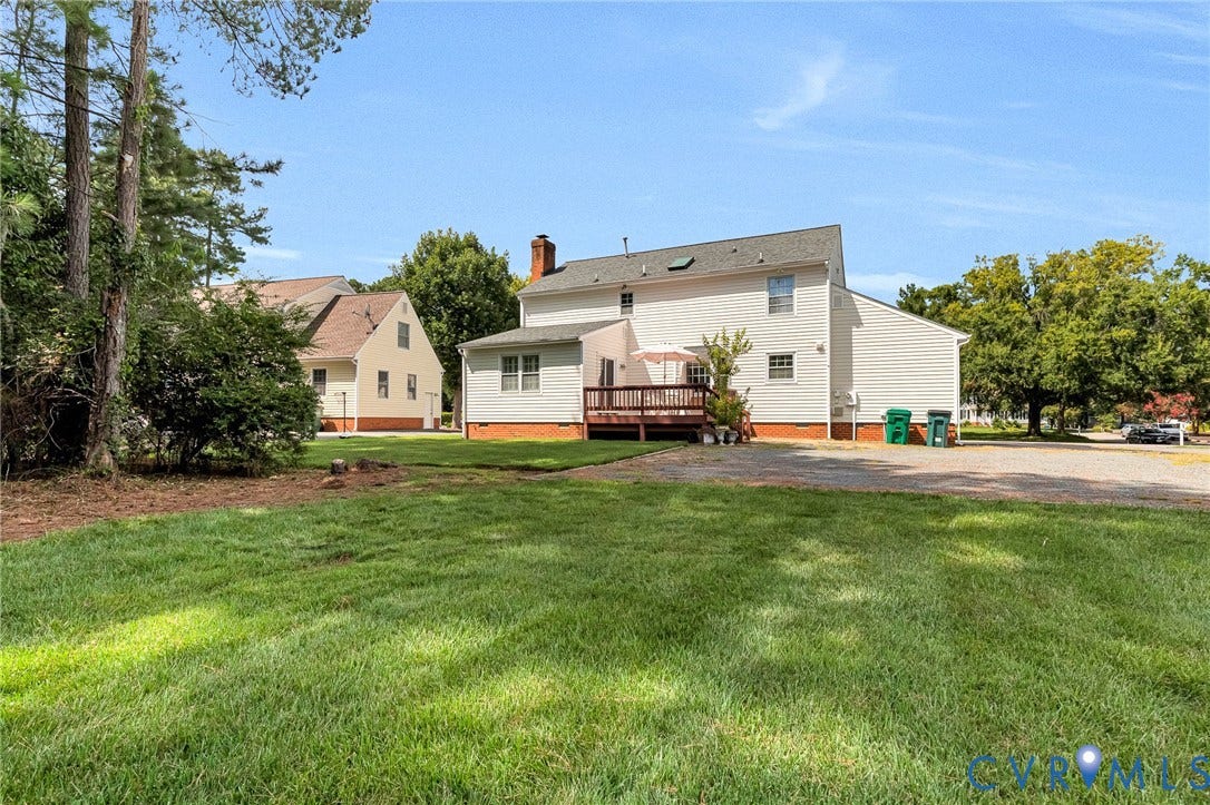 Expansive green lawn, mature trees, and a spacious rear deck
