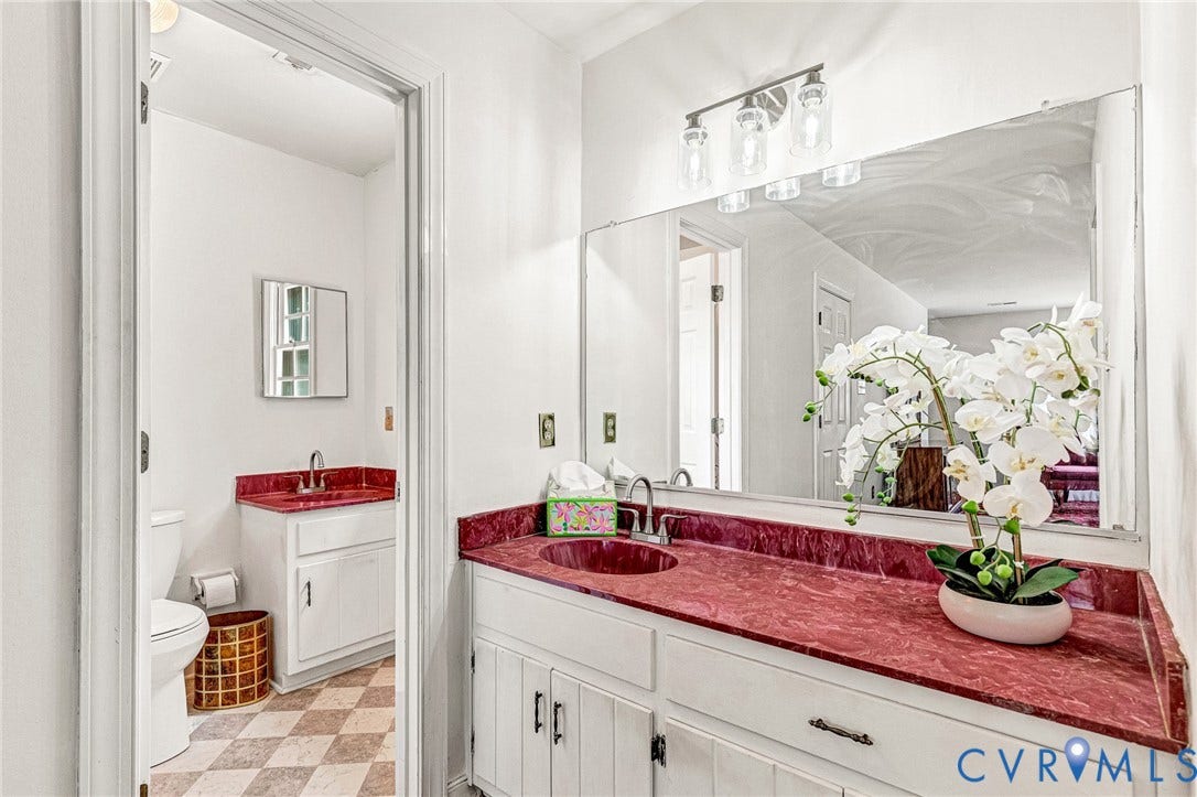 Dual vanity with red countertop, integrated sink, and white cabinetry