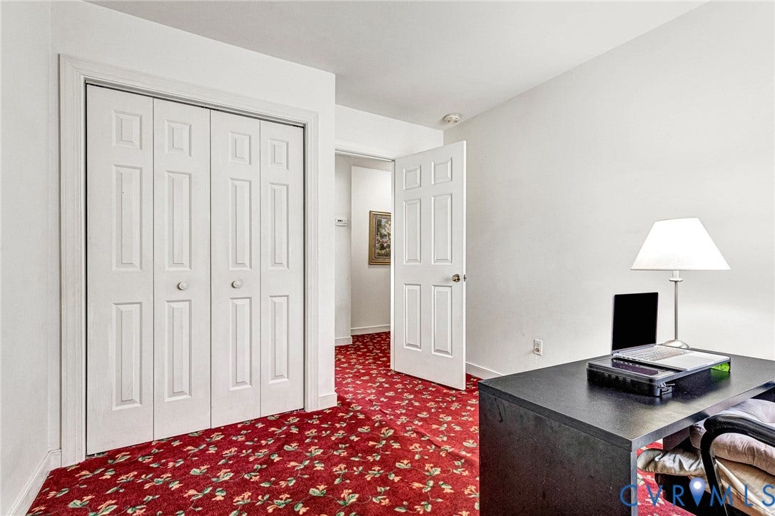 White paneled bifold doors with round knobs, six-panel interior door, and patterned red carpeting