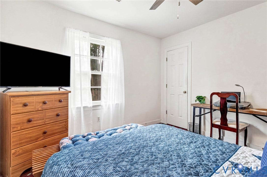 White walls, window with natural light, paneled door, wood-finish flooring, and a ceiling fan