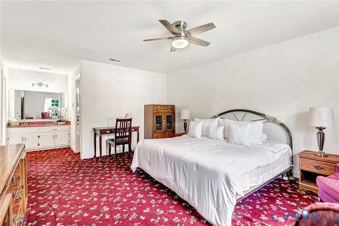 Spacious room featuring a ceiling fan, a vanity with ample counter space, a large mirror, and built-in white cabinetry