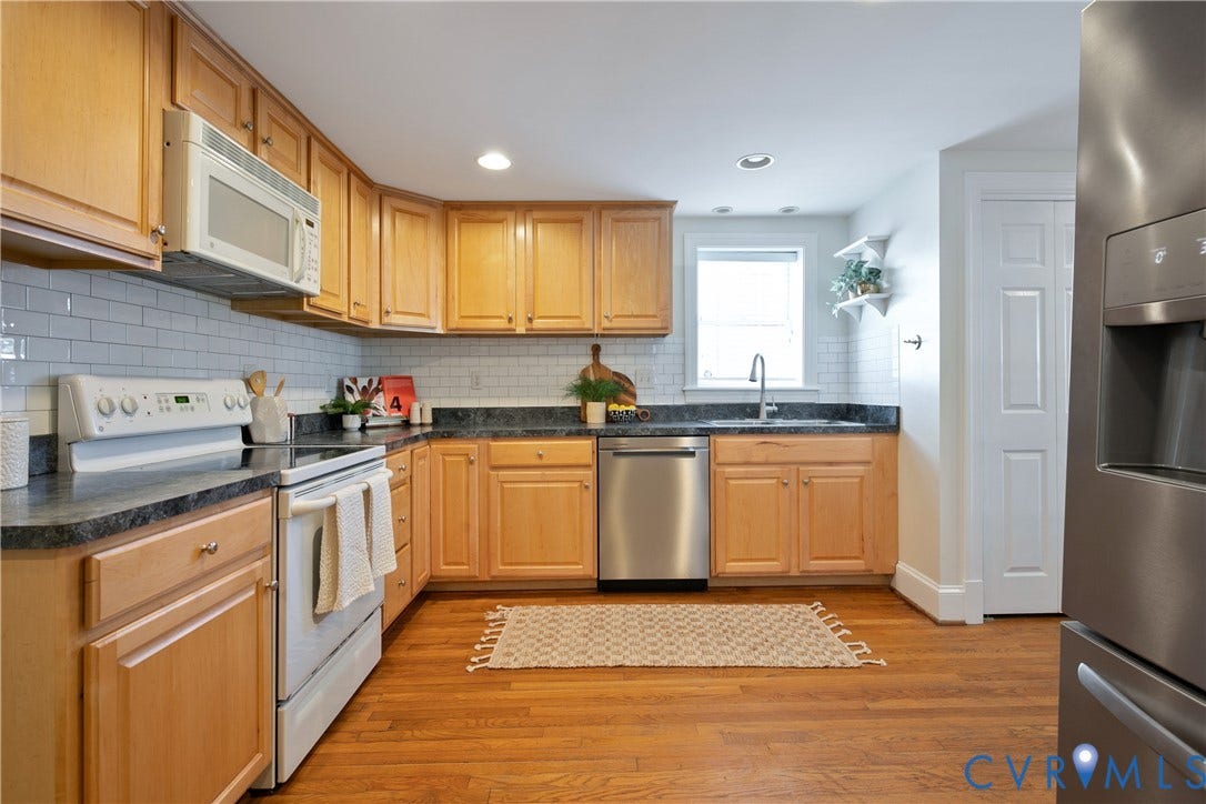518 N 1st Street, Jackson Ward, Richmond, VA 23219 Warm wood cabinetry with stainless steel appliances, dark countertops, and white subway tile backsplash