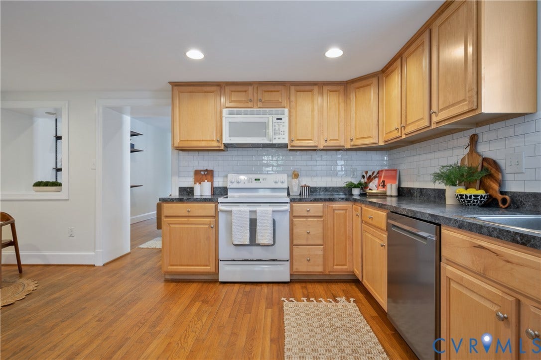 518 N 1st Street, Jackson Ward, Richmond, VA 23219 Spacious kitchen featuring warm wood cabinetry, stainless steel appliances, subway tile backsplash, dark countertops, and wood-finish flooring throughout the open layout