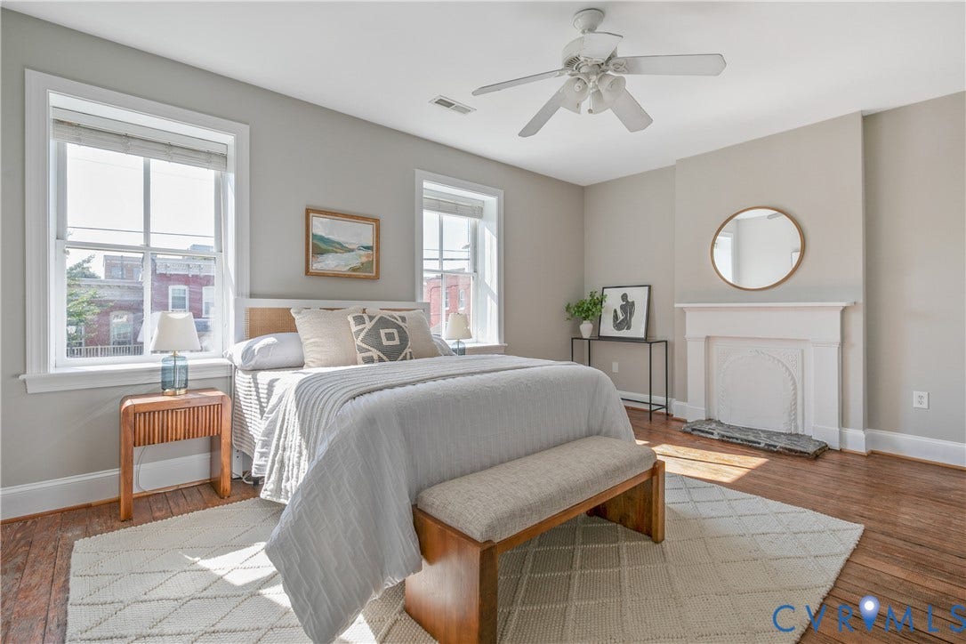 518 N 1st Street, Jackson Ward, Richmond, VA 23219 Hardwood flooring throughout, white ceiling fan with light fixture, two double-hung windows, and a decorative fireplace with a mantel